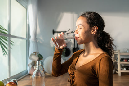 Mujer tomando agua en la cocina